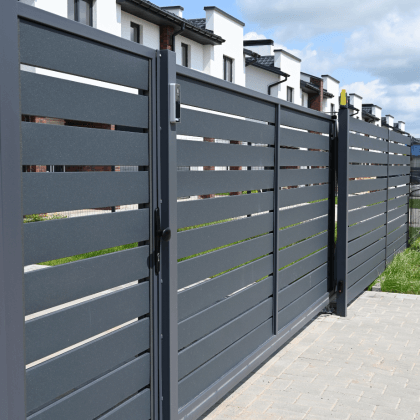 Modern black aluminum fence with wide horizontal slats surrounding a black and white apartment complex